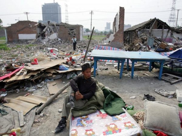 Một người từng là cư dân Bắc Kinh ngồi trên một tấm nệm giữa đống đổ nát sau khi ngôi nhà của ông bị phá hủy ở Bắc Kinh, Trung Quốc, vào ngày 10/05/2007. (Ảnh: China Photos/Getty Images)