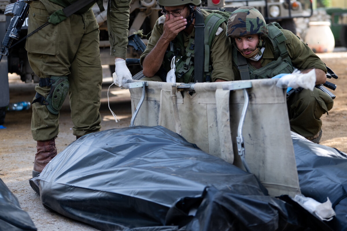 Một binh sĩ IDF phản ứng và che mặt trước khi đưa thi thể của một thường dân thiệt mạng vài ngày trước đó trong cuộc tấn công của chiến binh Hamas, hôm 10/10/2023, tại Kfar Aza, Israel. (Ảnh: Alexi J. Rosenfeld/Getty Images)