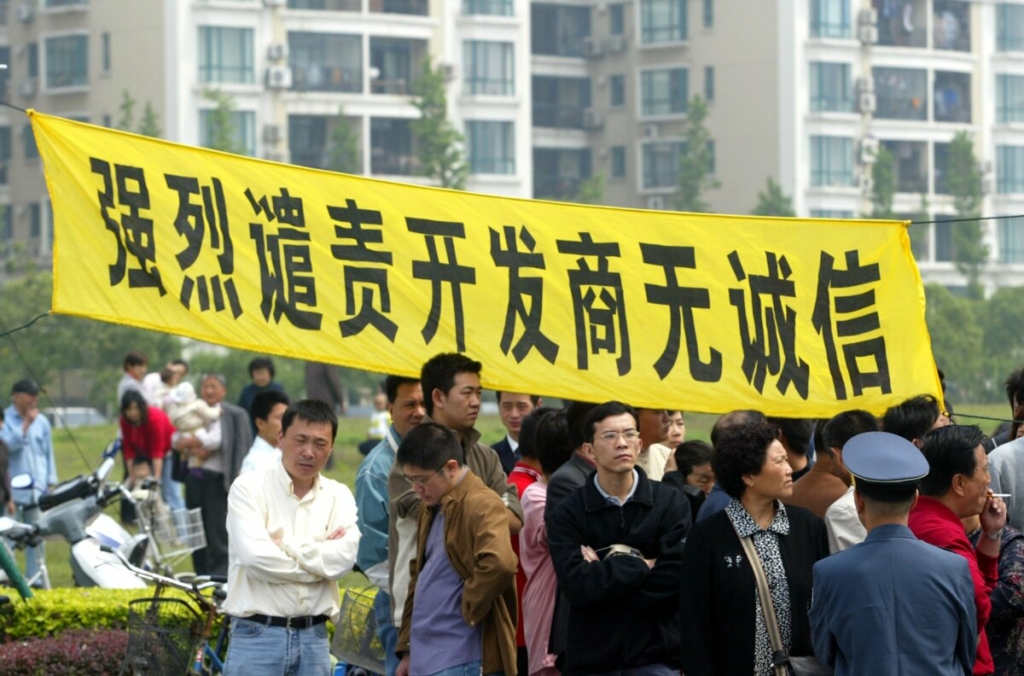 Người mua nhà treo biểu ngữ có dòng chữ “Mạnh mẽ lên án các nhà phát triển địa ốc không trung thực” trong một cuộc biểu tình tại Khu dân cư Cannes Thượng Hải ở Thượng Hải vào ngày 14/05/2006. (Ảnh: China Photos/Getty Images)