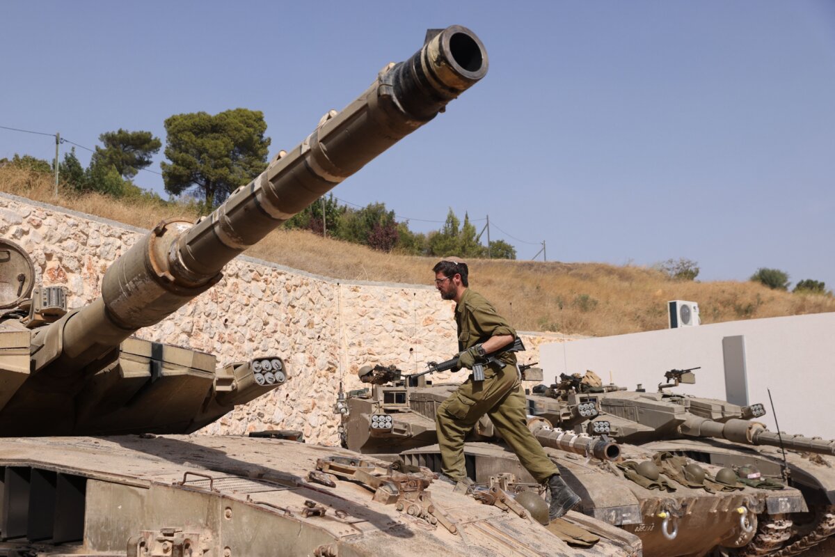 Một binh sĩ Israel bước đi trên chiếc xe tăng Merkava tại vị trí ở một địa điểm không được tiết lộ ở biên giới với Lebanon hôm 22/10/2023. (Ảnh: Jalaa Marey/AFP qua Getty Images)