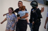 Các nhân viên cảnh sát Israel di tản một gia đình khỏi địa điểm bị trúng hỏa tiễn bắn từ Dải Gaza, ở Ashkelon, miền nam Israel, hôm 07/10/2023. (Ảnh: AP Photo/Tsafrir Abayov)