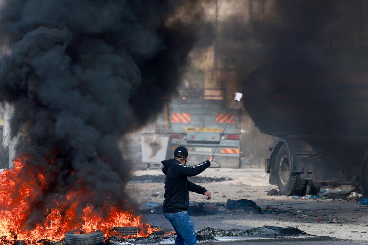 Một người Palestine sử dụng súng cao su trong cuộc đụng độ với binh sĩ Israel ở lối vào phía bắc của thành phố Ramallah của người Palestine, gần khu định cư Do Thái Beit El ở Tây Ngạn, hôm 13/10/2023. (Ảnh: Jaafar Ashtiyeh/AFP qua Getty Images)