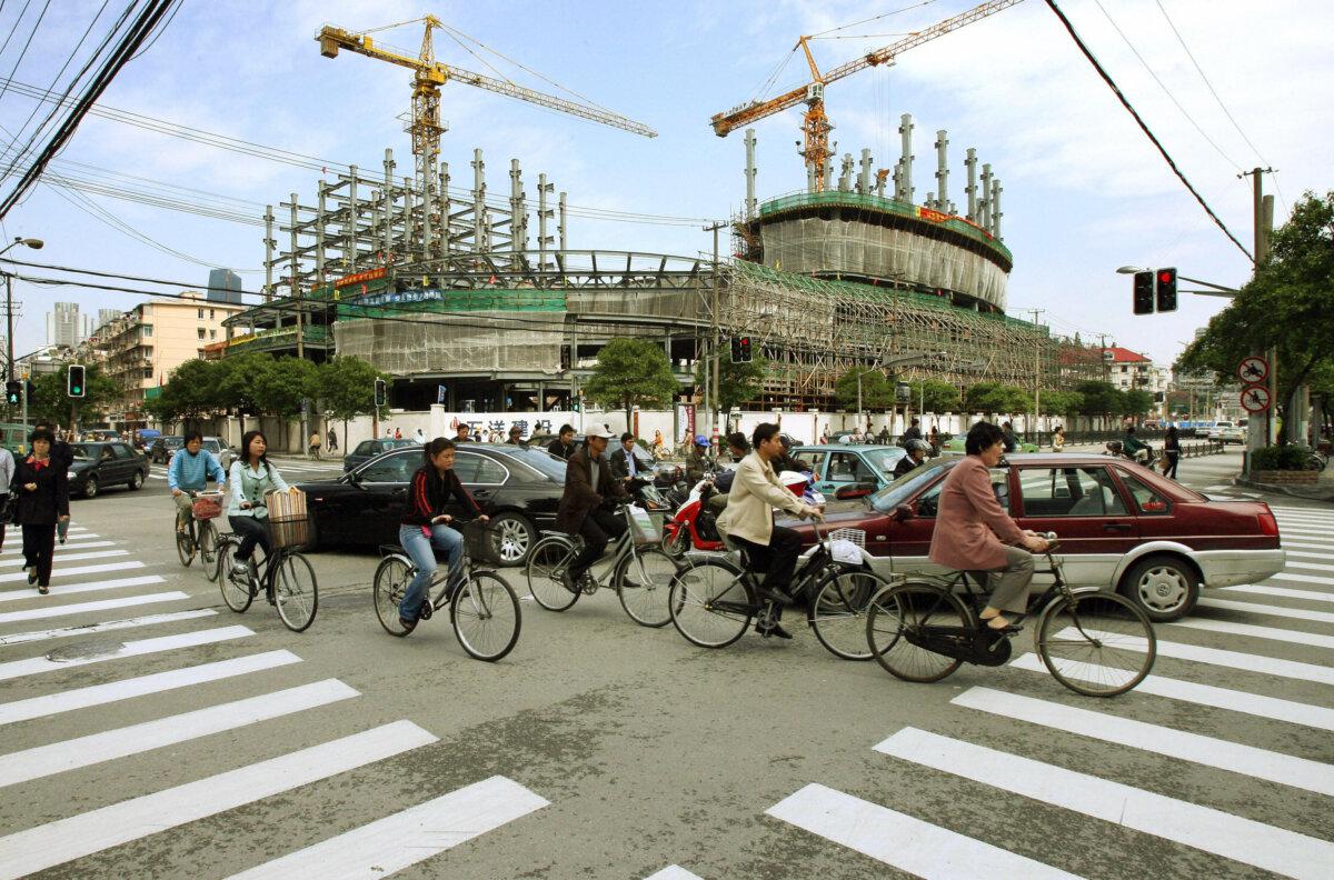 Xe cộ lưu thông qua lại trước một khu phát triển địa ốc lớn đang được xây dựng ở Thượng Hải, vào sáng sớm ngày 19/05/2006. (Ảnh: Mark Ralston/AFP qua Getty Images)