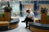 Một người đàn ông kiểm tra điện thoại khi đang nghỉ ngơi tại một trung tâm mua sắm ở Bắc Kinh hôm 18/07/2023. (Ảnh: Greg Baker/AFP qua Getty Images)