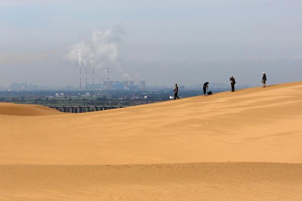 Khách du lịch đi bộ trên cồn cát gần một nhà máy điện ở sa mạc Hưởng Sa Loan (Xiangshawan) ở khu vực Ordos của Nội Mông trong bức ảnh tư liệu này. Các nhà khai thác bitcoin đã được hưởng mức giá điện ưu đãi ở những nơi như Ordos trong một thời gian dài. (Ảnh: Feng Li/Getty Images)