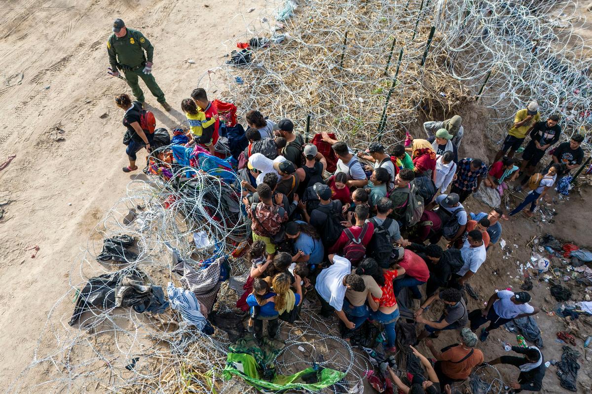 Góc nhìn từ trên không, một nhân viên Lực lượng Tuần tra Biên giới Hoa Kỳ nhìn những người nhập cư trái phép bước vào Hoa Kỳ sau khi băng qua Rio Grande từ Mexico, tại Eagle Pass, Texas, hôm 30/09/2023. (Ảnh: John Moore/Getty Images)