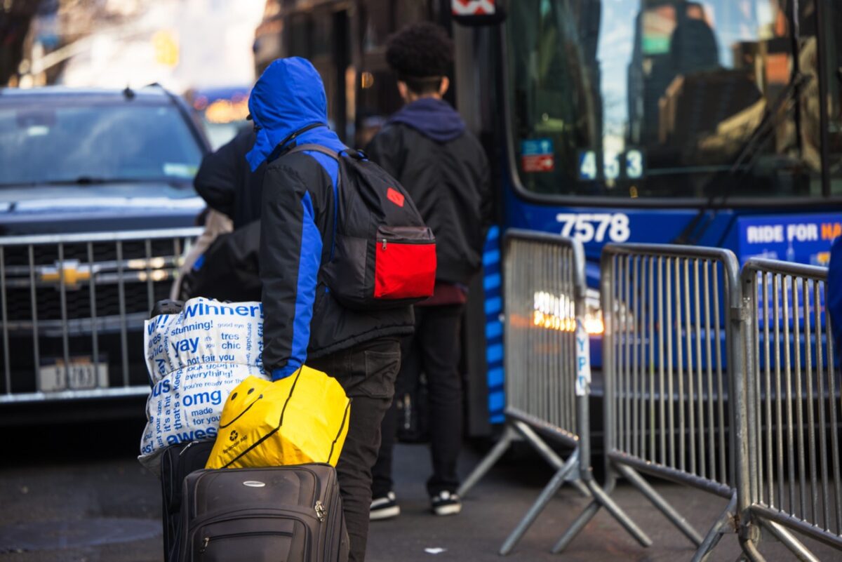 Những người nhập cư bất hợp pháp mang tư trang của họ lên xe bus sau khi chấp nhận di chuyển chỗ ở khi bị đuổi khỏi Khách sạn Watson ở thành phố New York hôm 30/01/2023. (Ảnh: Michael Santiago/Getty Images)
