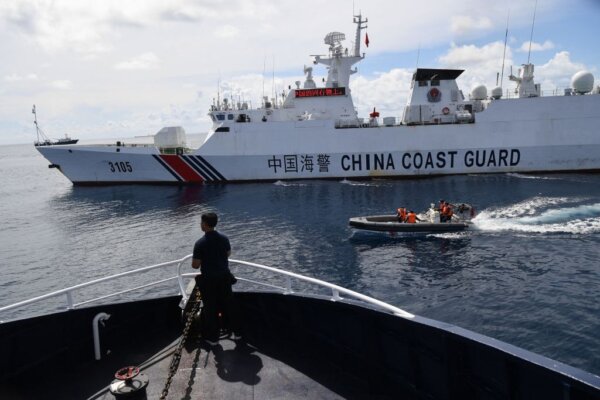 Một tàu hải cảnh Trung Quốc (phải) chặn tàu của Cục Nghề cá và Nguồn lợi Thủy sản Philippines (BFAR) (trái) trong lúc nhân viên của tàu Trung Quốc đang lên một chiếc thuyền bơm hơi thân cứng đi ngang qua tàu Philippines, khi tàu này đến gần Bãi cạn Scarborough ở Biển Đông đang tranh chấp hôm 22/09/2023. (Ảnh: Ted Aljibe/AFP qua Getty Images)