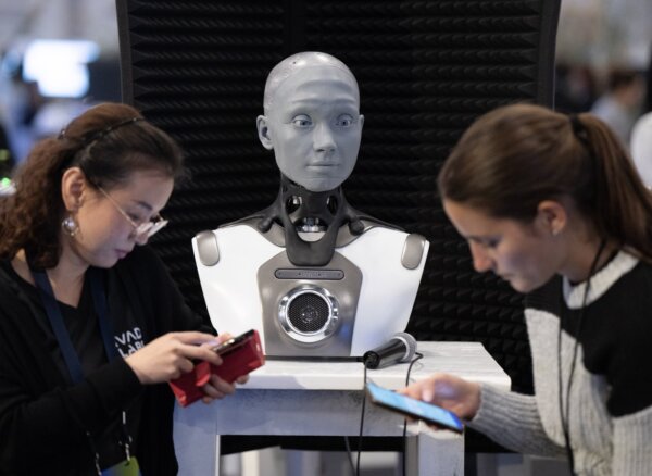 Mọi người kiểm tra điện thoại của họ khi AMECA, một robot AI, quan sát tại hội nghị trí tuệ nhân tạo All In ở Montreal hôm 28/09/2023. (Ảnh: The Canadian Press/Ryan Remiorz)