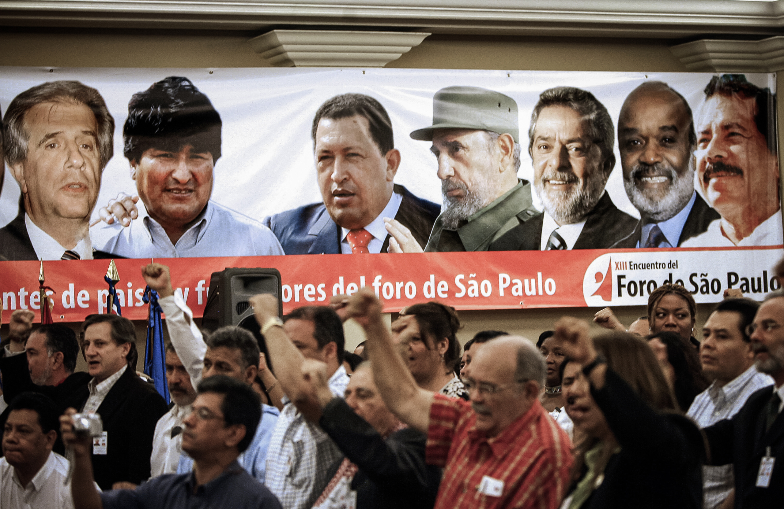 Những người tham dự hô khẩu hiệu trong lễ khai mạc Diễn đàn Sao Paulo, bên cạnh một biểu ngữ có chân dung của các tổng thống cánh tả Mỹ Latinh, ở San Salvador, El Salvador, vào ngày 12/01/2007. (Ảnh: Yuri Cortez/AFP qua Getty Images)