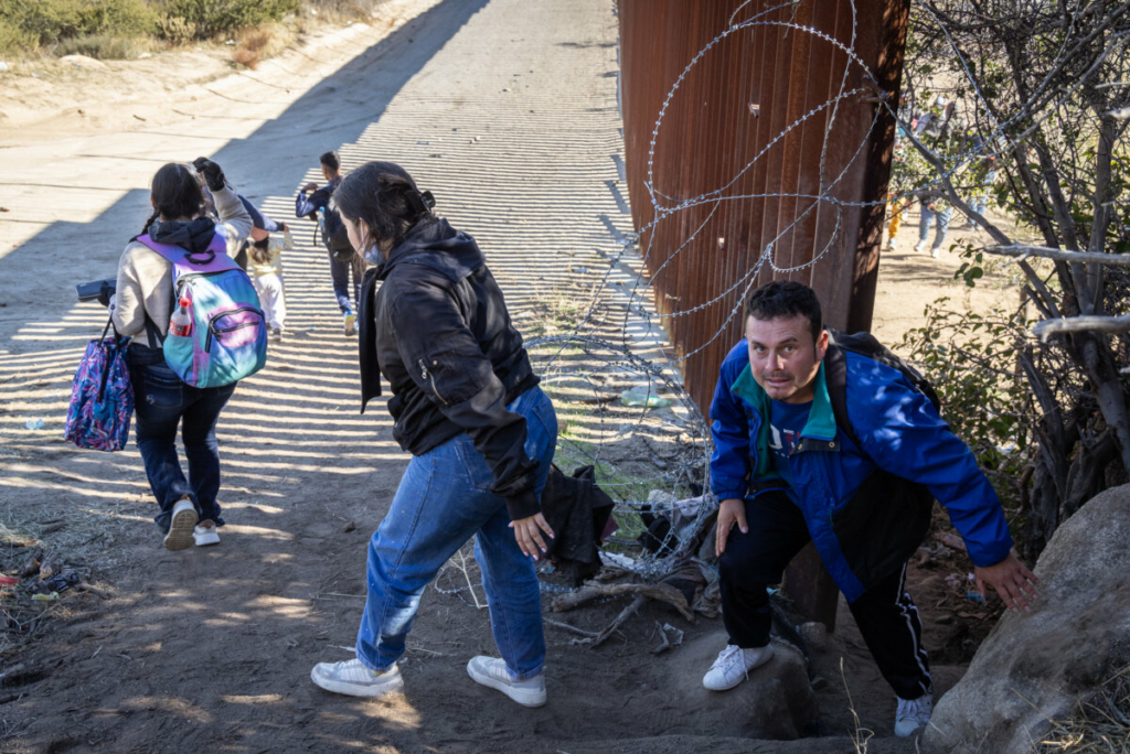 Những người nhập cư bất hợp pháp đi qua một khoảng trống trên bức tường biên giới Hoa Kỳ để chờ các nhân viên Tuần tra Biên giới đến giải quyết, ở Jacumba, California, hôm 07/12/2023. (Ảnh: John Fredricks/The Epoch Times)