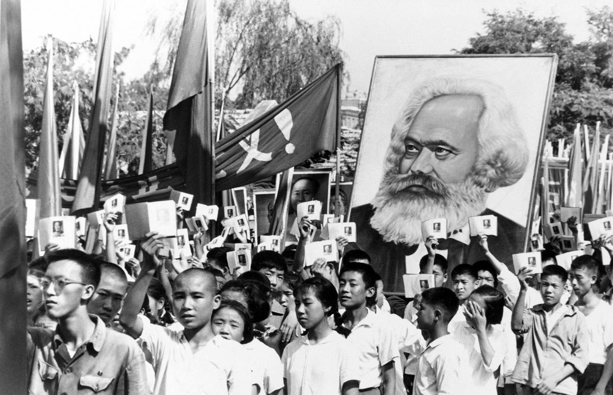 Những thanh niên tại một cuộc mít-tinh trong thời kỳ cao trào của cuộc biến động Hồng vệ binh đang vẫy các cuốn Tiểu Hồng Thư của ông Mao Trạch Đông và mang theo một tấm bích chương có hình ông Karl Marx vào ngày 14/09/1966. Cách mạng Văn hóa đã khởi đầu một thập niên đầy bạo lực và hỗn loạn nhằm đạt được các mục tiêu cộng sản và thực thi một chính sách chủ nghĩa quân bình cực đoan. (Ảnh: AP Photo)