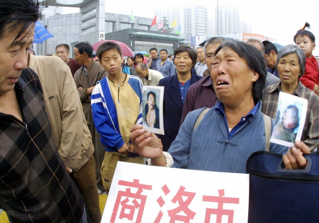Một người nông dân khóc khi cầm những bức ảnh của người con trai mà bà cho rằng đã bị chính quyền địa phương đánh đập và sát hại, khi bà cùng với những người khiếu kiện khác xếp hàng bên ngoài văn phòng khiếu nại mới chờ cơ hội gửi khiếu nại ở Tây An, tỉnh Thiểm Tây, miền trung Trung Quốc vào ngày 18/18/2005. (Ảnh: STR/AFP qua Getty Images)