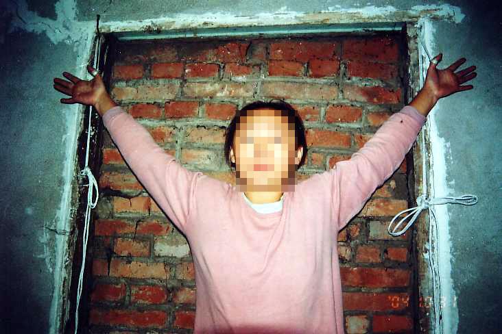 Tái hiện cảnh tra tấn bằng cách treo người bằng một sợi dây buộc quanh ngón cái. (Ảnh: Được đăng dưới sự cho phép của Minghui.org)
