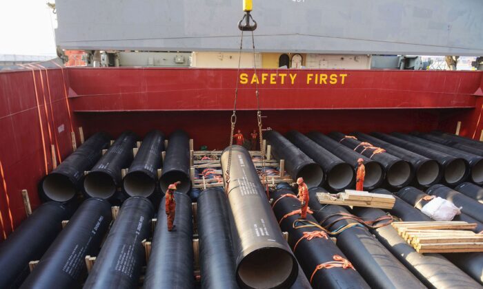 Công nhân đang chất các đường ống sẽ được xuất cảng sang châu Phi lên boong tàu tại một cảng ở Thanh Đảo, tỉnh Sơn Đông, miền đông Trung Quốc vào ngày 01/04/2019. (Ảnh: STR/AFP/Getty Images)