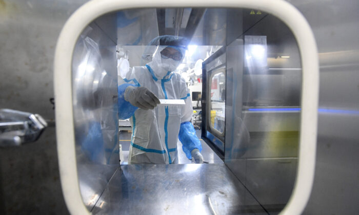 Một kỹ thuật viên phòng thí nghiệm mặc thiết bị bảo hộ cá nhân (PPE) đang nghiên cứu các mẫu xét nghiệm virus Corona gây Covid-19 tại phòng thí nghiệm Fire Eye, cơ sở xét nghiệm Covid-19, ở Vũ Hán, Trung Quốc, vào ngày 05/08/2021. (Ảnh của STR/ AFP qua Getty Images)