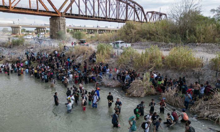Những người di cư chờ đợi ở Rio Grande để mở hàng rào dây thép gai, để đi vào Hoa Kỳ, ở Eagle Pass, Texas, hôm 25/09/2023. (Ảnh: Andrew Caballero-Reynolds/AFP qua Getty Images)