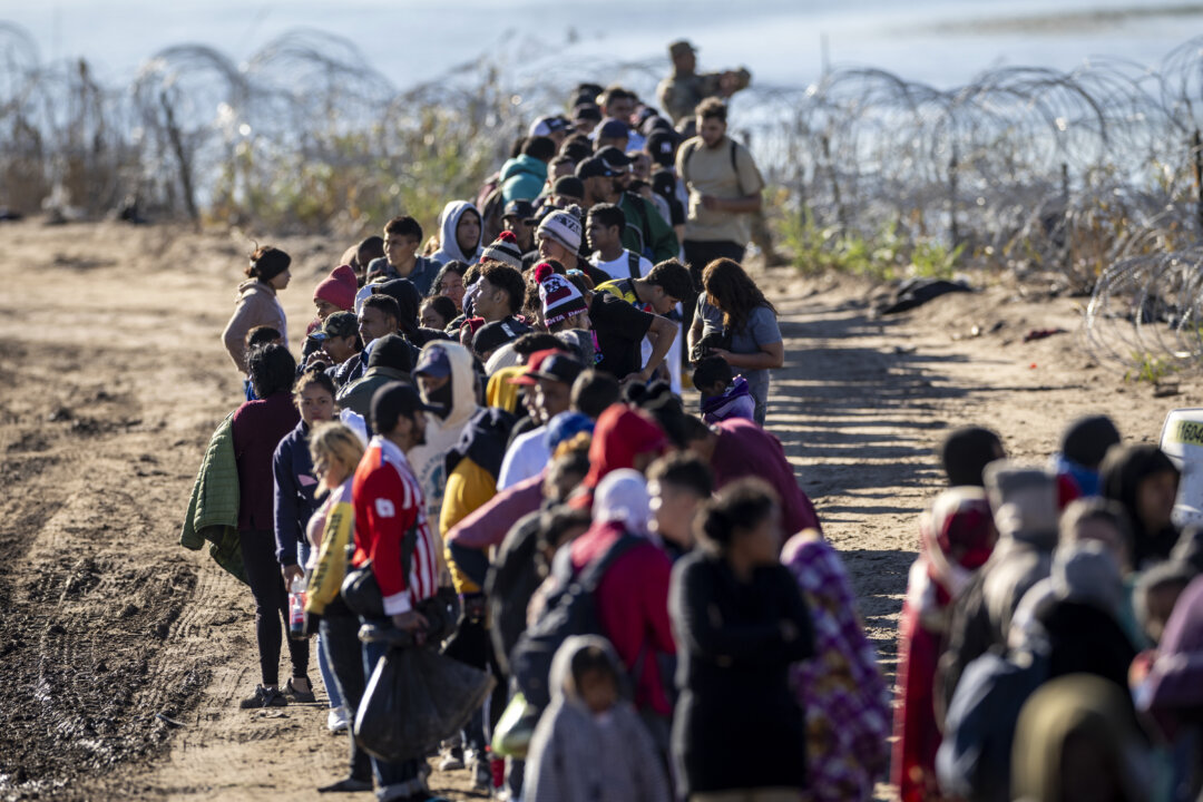 Sau khi từ Mexico băng qua sông Rio Grande, hơn 1,000 người nhập cư không được thẩm tra chặt chẽ xếp hàng chờ ở gần một trung tâm giải quyết hiện trường của Lực lượng Tuần tra Biên giới Hoa Kỳ, ở Eagle Pass, Texas, hôm 18/12/2023. (Ảnh: John Moore/Getty Images)