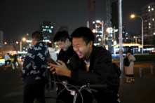 Học sinh chơi trò chơi điện tử trên điện thoại khi chờ ở ngã tư trong giờ cao điểm ở Bắc Kinh, Trung Quốc, hôm 15/11/2023. (Ảnh: Kevin Frayer/Getty Images)