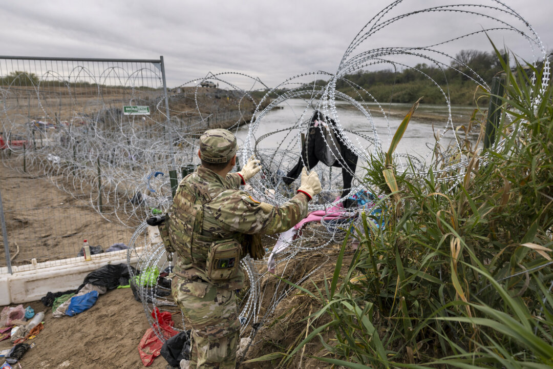 Một binh sĩ thuộc Lực lượng Vệ binh Quốc gia Texas lắp thêm dây thép gai tại biên giới Hoa Kỳ-Mexico ở Eagle Pass, Texas hôm 20/12/2023. (Ảnh: John Moore/Getty Images)