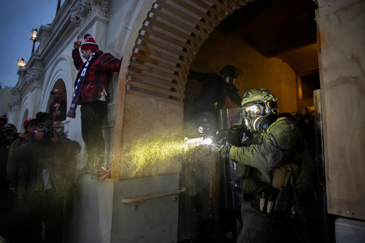 Một nhân viên Cảnh sát Tòa nhà Quốc Hội bắn thứ có vẻ như hơi cay vào những người biểu tình tại Tòa nhà Quốc Hội Hoa Kỳ ở Hoa Thịnh Đốn, vào ngày 06/01/2021. (Ảnh: Brent Stirton/Getty Images)