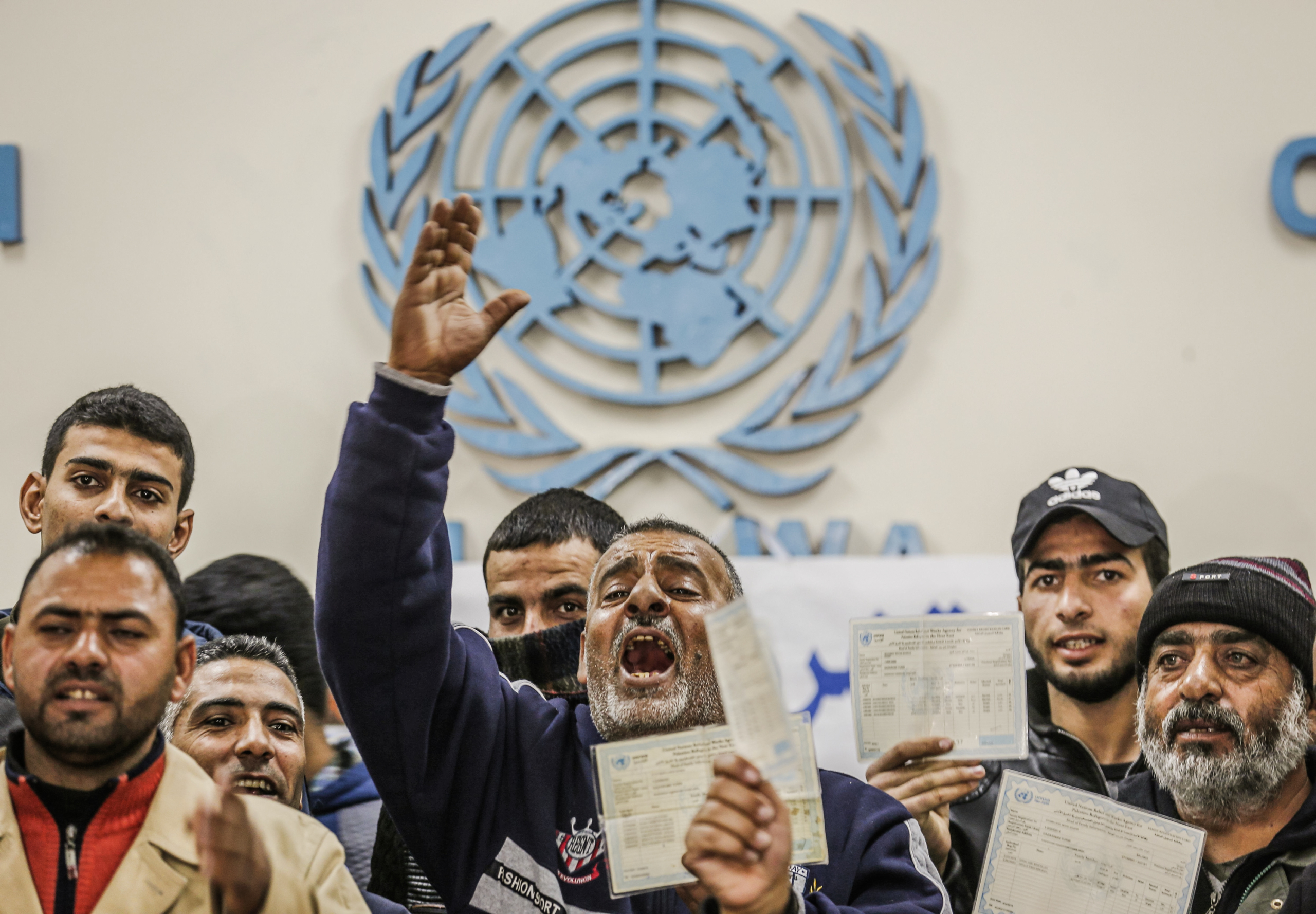 Một người đàn ông cầm thẻ tị nạn đang hô khẩu hiệu trong cuộc biểu tình kêu gọi Cơ quan Liên Hiệp Quốc về Cứu trợ và Việc làm cho Người tị nạn Palestine trả tiền cho người Palestine để sửa chữa nhà cửa của họ, bị hư hại trong cuộc xung đột Israel-Gaza năm 2014, tại một phòng khám của UNRWA ở phía nam Dải Gaza vào ngày 09/12/2019. (Ảnh: Said Khatib/AFP cho biết qua Getty Images)