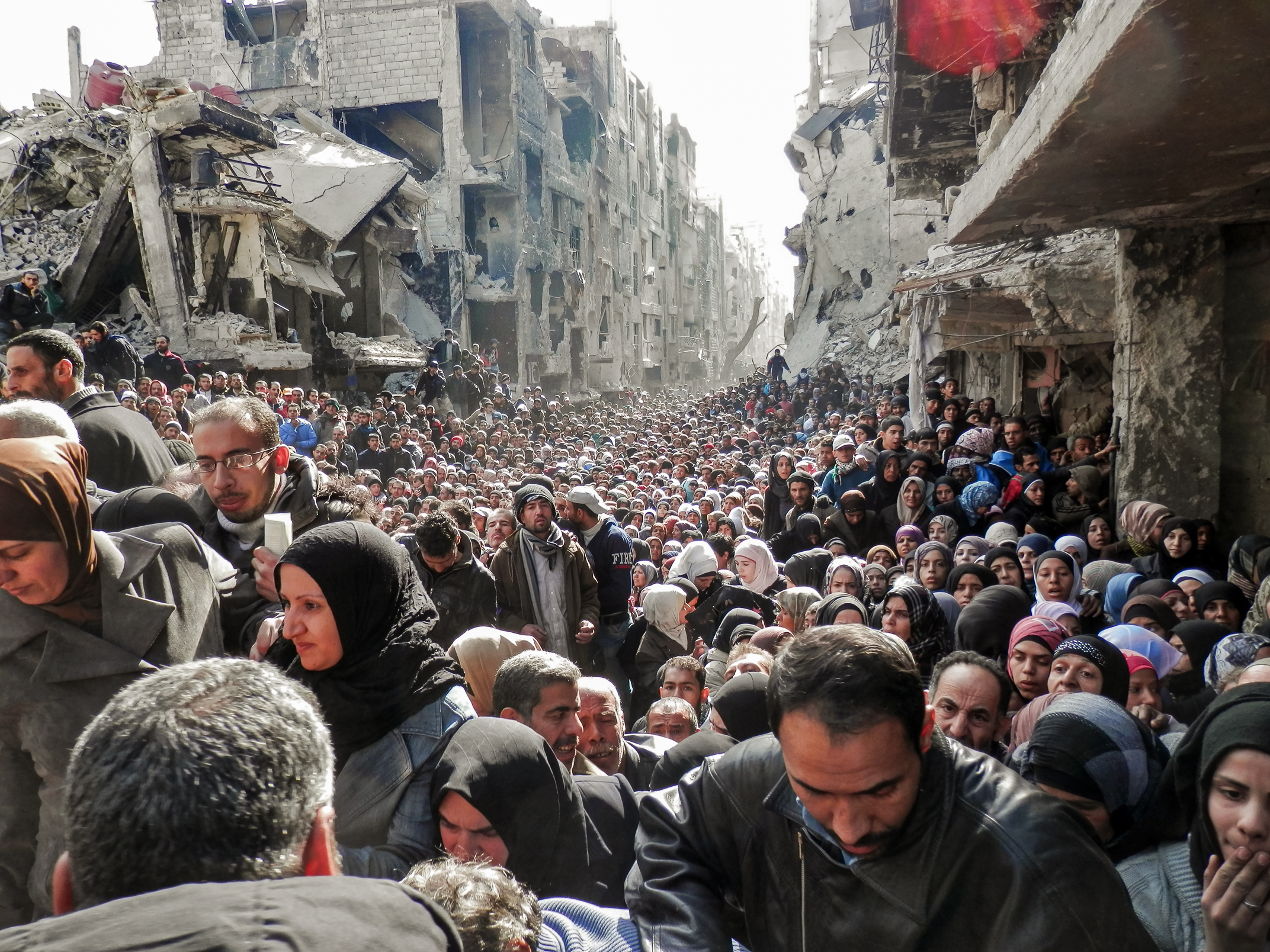 Người dân xếp hàng chờ nhận lương thực viện trợ được phân phát tại trại tị nạn Yarmouk ở Damascus, Syria, vào ngày 31/01/2014. (Ảnh: Cơ quan Liên Hiệp Quốc về Cứu trợ và Việc làm qua Getty Images)
