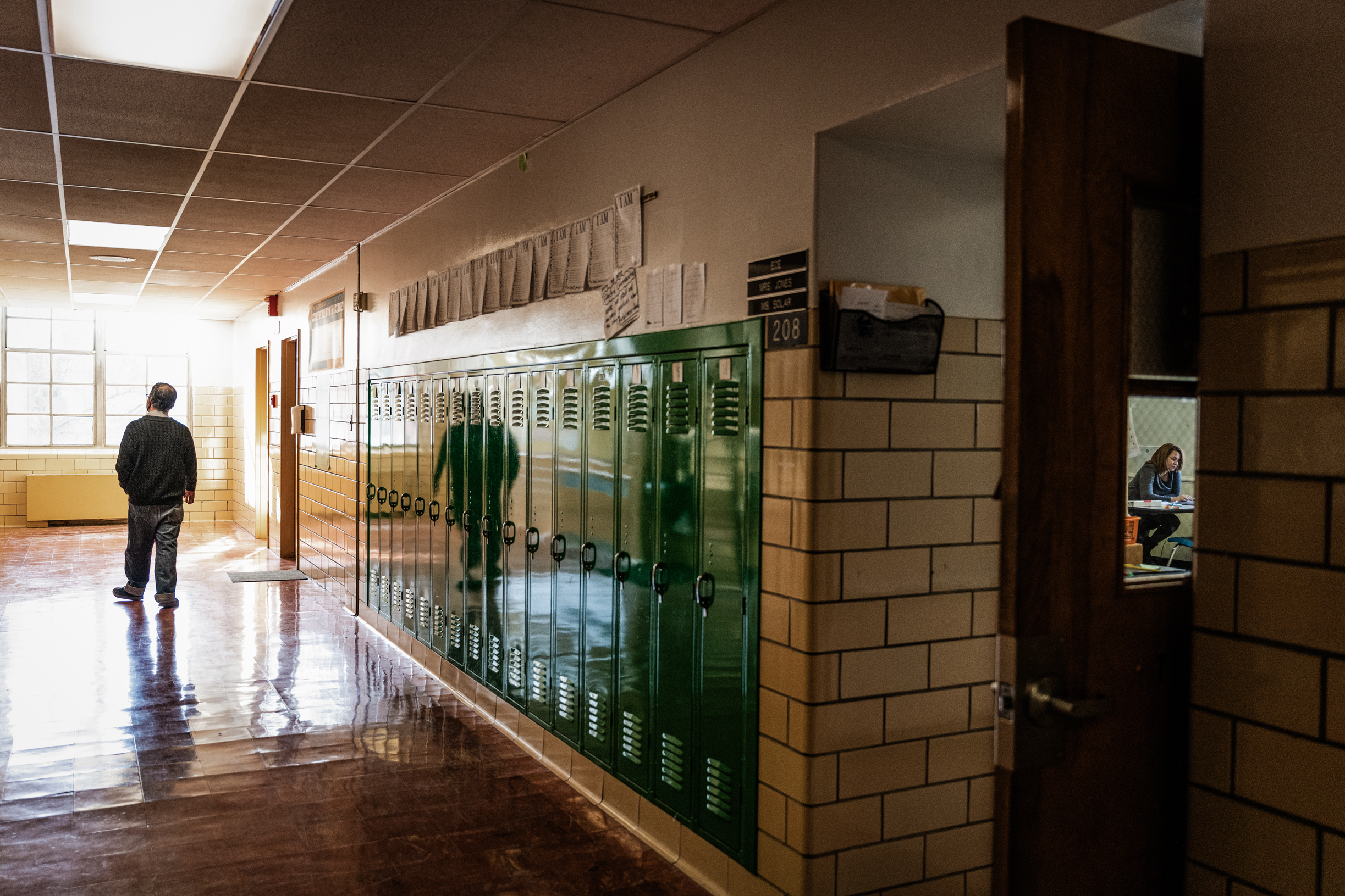 Một giáo viên bước xuống hành lang trống trong khi một giáo viên khác dạy trực tuyến (phải) tại Trường tiểu học Hazelwood ở Louisville, Kentucky, vào ngày 11/01/2022. (Ảnh: Jon Cherry/Getty Images)