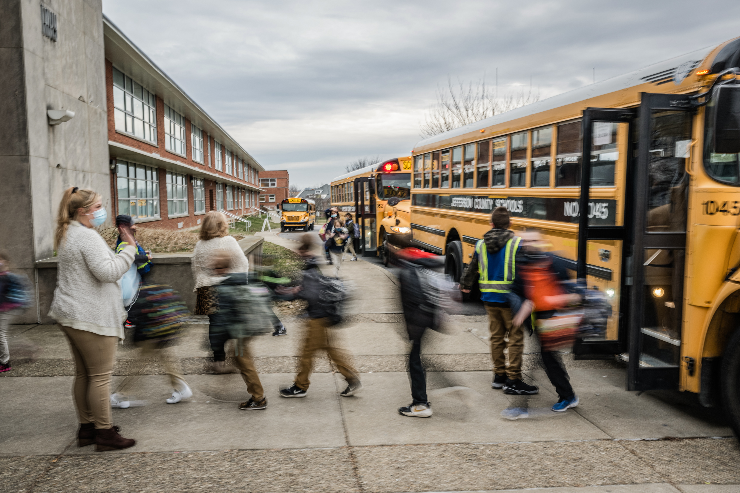Giáo viên vẫy tay chào học sinh khi các em xuống xe buýt tại Trường Tiểu học Truyền thống Carter ở Louisville, Kentucky, vào ngày 24/01/2022. (Ảnh: Jon Cherry/Getty Images)