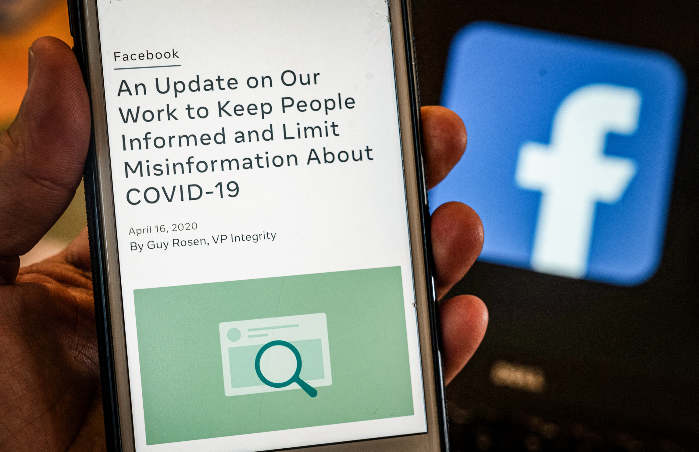 Màn hình điện thoại thông minh hiển thị một chính sách mới về thông tin sai lệch COVID-19 với trang web Facebook ở phía sau, ở Arlington, Virginia, ngày 27/05/2021. (Ảnh: Andrew Caballero-Reynolds/AFP qua Getty Images)