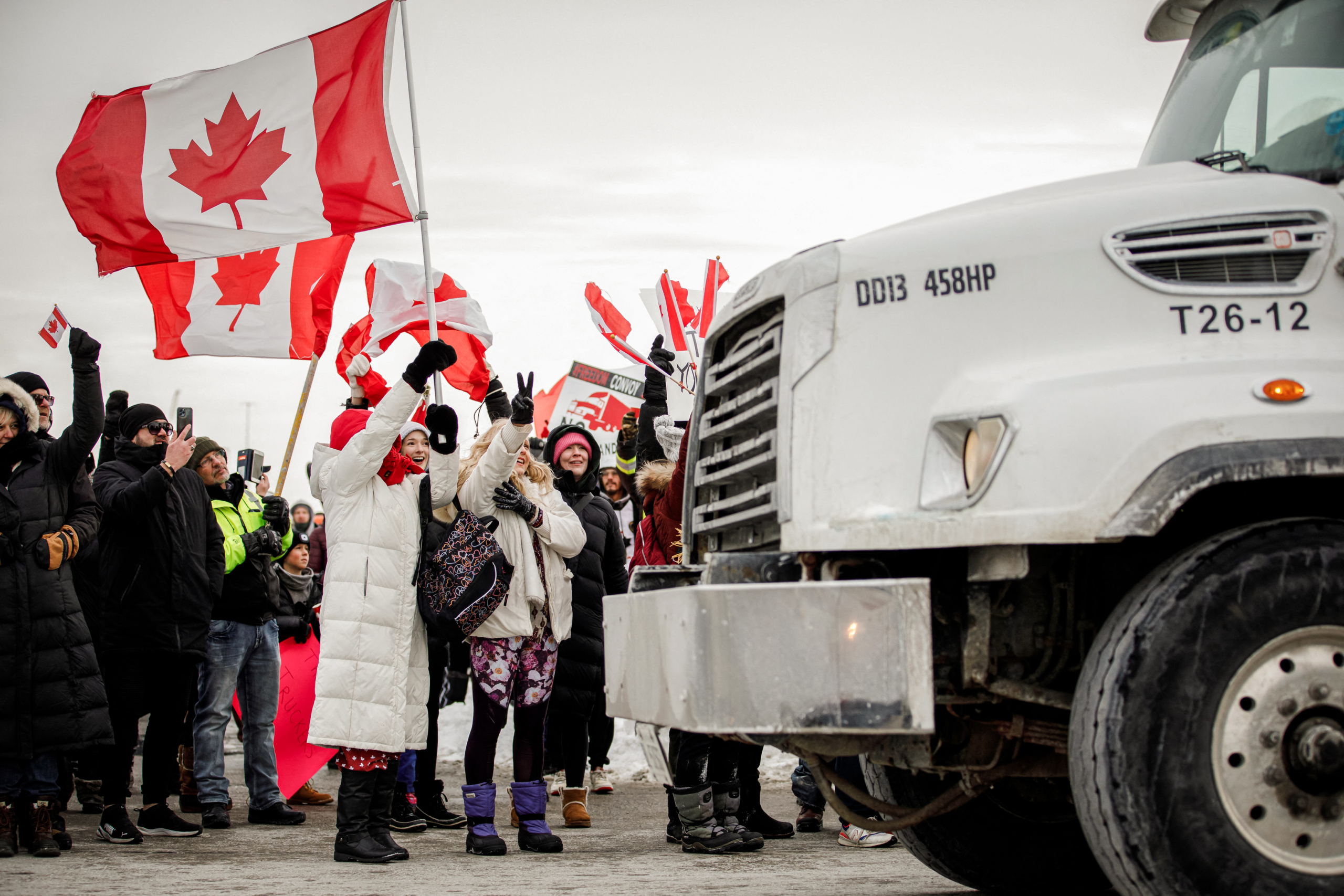 Những người ủng hộ đoàn tài xế xe tải phản đối quy định chích vaccine COVID-19 cho tài xế xe tải chạy xuyên biên giới đang tập trung gần một cầu vượt đường cao tốc bên ngoài Toronto, Canada, vào ngày 27/01/2022. (Ảnh: Cole Burston/AFP qua Getty Images)