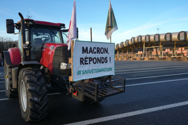 Một chiếc máy kéo mang tấm bảng có dòng chữ “Ông Macron, hãy trả lời! Hãy cứu nông dân của ông” tại một cuộc phong tỏa của nông dân biểu tình đối với tuyến xa lộ A10 trong cuộc biểu tình phản đối thuế và thu nhập giảm sút, gần cổng thu phí Peage de Saint-Arnoult-en-Yvelines ở phía tây nam Paris, hôm 26/01/2024, trong ngày biểu tình toàn quốc do một số liên đoàn nông dân kêu gọi về lương, thuế, và các quy định. (Ảnh: Dimitar Dilkoff/AFP)