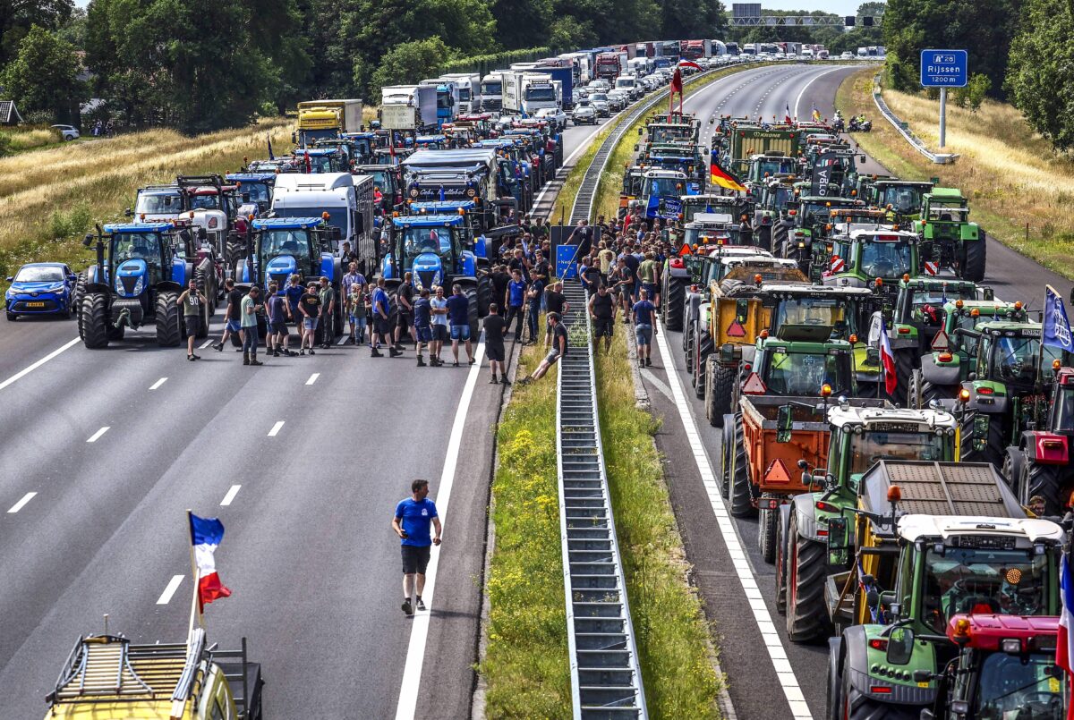 Nông dân tập hợp cùng nhau trên phương tiện của họ cạnh một biển báo biên giới Đức/Hà Lan trong cuộc biểu tình tại đường cao tốc A1, gần Rijssen, ngày 29/06/2022. (Ảnh: Vincent Jannink/ANP/AFP qua Getty Images)