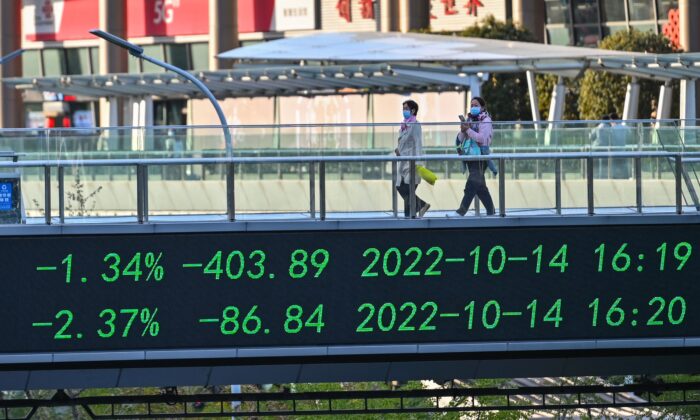 Người đi bộ sải bước qua cây cầu có bảng hiển thị các chỉ báo chứng khoán ở khu tài chính Lục Gia Chủy ở Thượng Hải, Trung Quốc, hôm 17/10/2022. (Ảnh: Hector Retamal/AFP qua Getty Images)