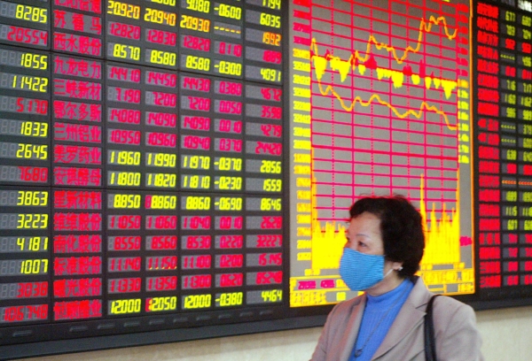 Một nhà đầu tư đi ngang qua bảng chỉ số giá cổ phiếu tại sở giao dịch chứng khoán ở Thượng Hải, Trung Quốc, ngày 12/05/2003. (Ảnh: Liu Jin/AFP qua Getty Images)