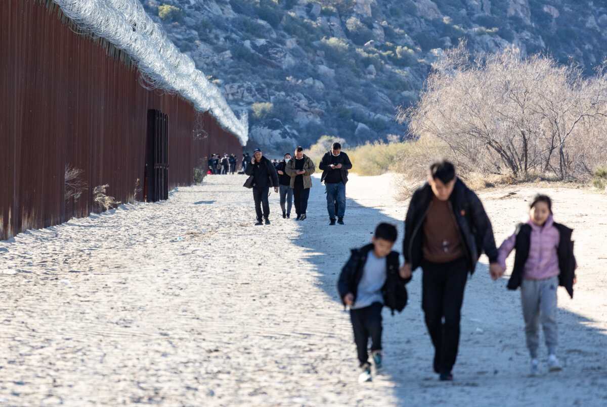 Những người di cư đi dọc bức tường biên giới bên phía Hoa Kỳ sau khi băng qua một khoảng trống ở Jacumba, California, hôm 06/12/2023. (Ảnh: John Fredricks/The Epoch Times)