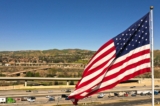 Xe hơi và xe tải chạy ngang qua một lá cờ Hoa Kỳ trên Xa lộ 91 ở Anaheim Hills, California, hôm 08/02/2023. (Ảnh: Patrick T. Fallon/AFP qua Getty Images)