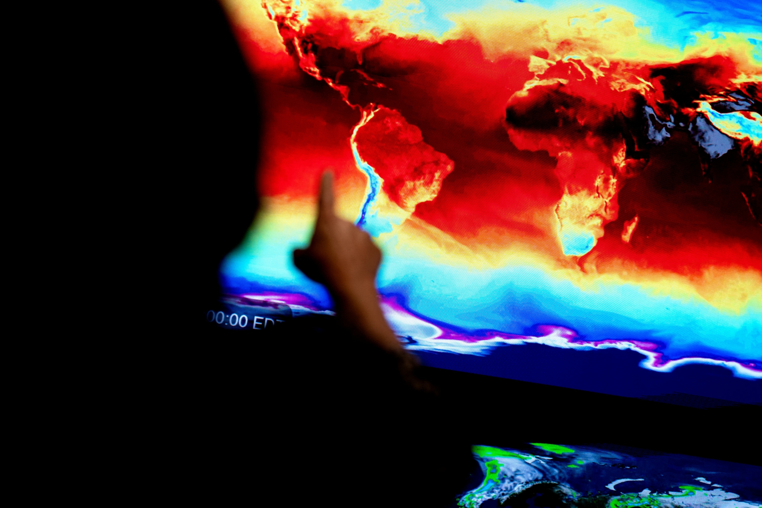 Một nhân viên chỉ tay về phía một bản đồ toàn cầu cho thấy thông tin đến từ các vệ tinh của NASA trong một cuộc triển lãm tại trụ sở NASA ở Hoa Thịnh Đốn vào ngày 21/06/2023. (Ảnh: Stefani Reynolds/AFP qua Getty Images)