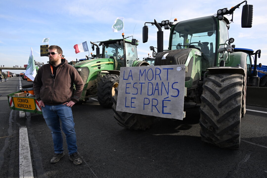 Một nông dân Pháp tham gia một cuộc biểu tình chặn đường trên xa lộ A4 bên cạnh một máy kéo có tấm biểu ngữ ghi “Sự chán chường đang hiện diện trên cánh đồng” gần Jossigny, ph
