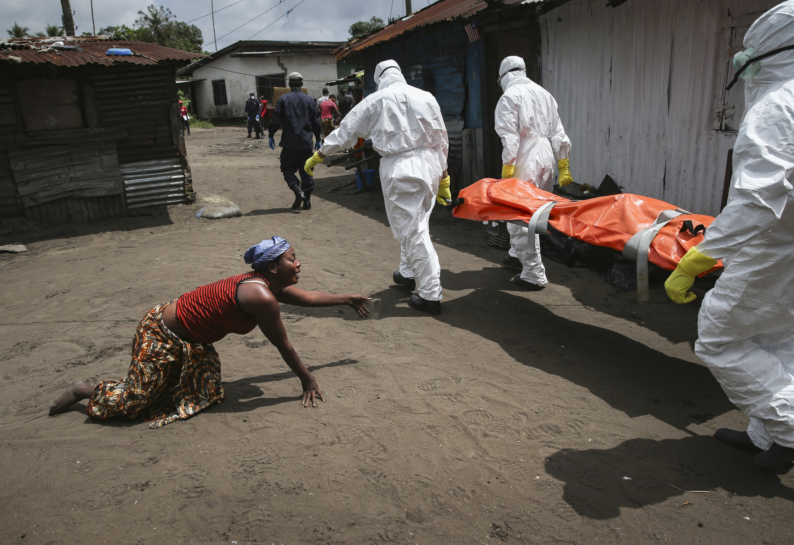 Một người phụ nữ bò về phía thi thể của em gái mình khi các thành viên đội mai táng dịch Ebola đưa thi thể đi hỏa táng ở Monrovia, Liberia, vào ngày 10/10/2014. (Ảnh: John Moore/Getty Images)