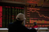 Các nhà đầu tư xem diễn biến giá cổ phiếu trên màn hình hiển thị giá cổ phiếu tại một công ty chứng khoán ở Bắc Kinh, Trung Quốc hôm 11/10/2018. (Ảnh: Nicolas Asfouri/AFP qua Getty Images)