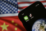 Trong hình ảnh minh họa này, có thể thấy một chiếc điện thoại di động hiển thị logo của hai ứng dụng WeChat và TikTok của Trung Quốc để trước một màn hình hiển thị cờ của Hoa Kỳ và Trung Quốc trên một trang mạng ở Bắc Kinh vào ngày 22/09/2020. (Ảnh: Kevin Frayer/Getty Images)