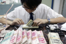 Một nhân viên đếm các tập tiền USD và nhân dân tệ tại một ngân hàng ở Thượng Hải, Trung Quốc, hôm 22/07/2005. (Ảnh: China Photos/Getty Images)
