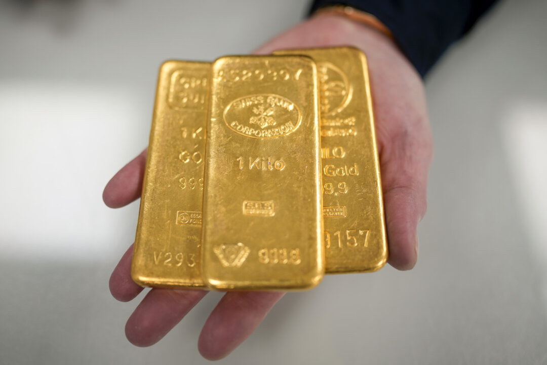Một người buôn vàng với ba thỏi vàng nặng 1 kg ở Birmingham, Anh, vào ngày 13/12/2023. (Ảnh: Christopher Furlong/Getty Images)