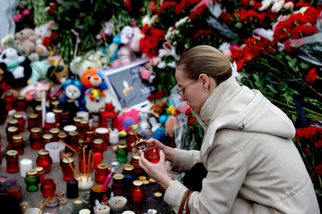 Một người phụ nữ thắp nến tại đài tưởng niệm các nạn nhân của một cuộc xả súng tại phòng hòa nhạc của Nhà hát Crocus City Hall gần Moscow, hôm 24/03/2024. (Ảnh: Maxim Shemetov/Reuters)