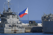 Cờ Philippines tung bay bên cạnh các tàu hải quân neo đậu tại đảo Thị Tứ do Philippines chiếm đóng ở Biển Đông đang tranh chấp, vào ngày 21/04/2023. (Ảnh: Ted Aljibe/Getty Images)