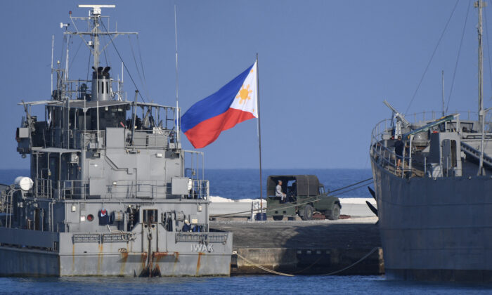 Cờ Philippines tung bay bên cạnh các tàu hải quân neo đậu tại đảo Thị Tứ do Philippines chiếm đóng ở Biển Đông đang tranh chấp, vào ngày 21/04/2023. (Ảnh: Ted Aljibe/Getty Images)