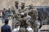 Các binh sĩ Vệ binh Quốc gia Texas phong tỏa một đoạn dây thép gai bao quanh trại di cư tạm thời khi một người nhập cư cố gắng trở về mang theo thức ăn cho gia đình ở El Paso, Texas, vào ngày 11/05/2023. (Ảnh: John Moore/Getty Images)