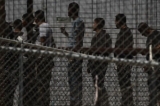 Những người nhập cư bất hợp pháp chờ dọc bức tường biên giới để lên xe buýt sau khi tự ra trình diện trước các nhân viên Tuần tra Biên giới và Cục Quan thuế và Bảo vệ Biên giới Hoa Kỳ (CBP) ở biên giới Hoa Kỳ-Mexico ở El Paso, Texas, vào ngày 12/05/2023. (Ảnh: Patrick T. Fallon/ AFP qua Getty Images)