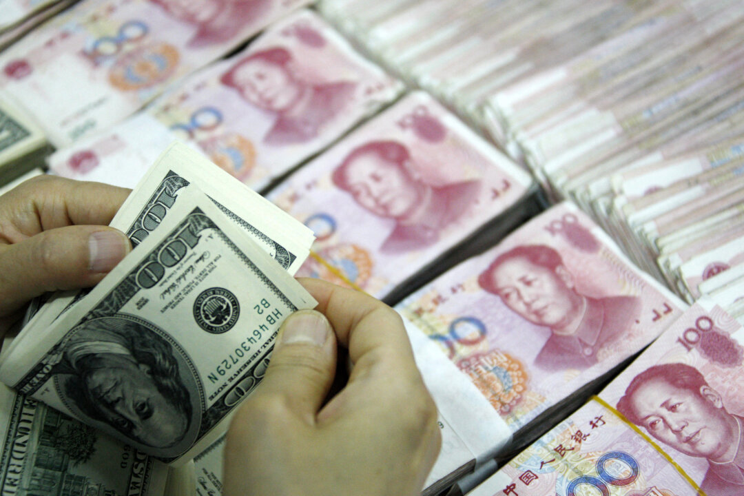 Nhân viên đếm USD bên cạnh các tập tiền 100 nhân dân tệ (RMB) tại một ngân hàng ở Hoài Bắc, Trung Quốc, ngày 24/09/2013. (Ảnh: STR/AFP qua Getty Images)